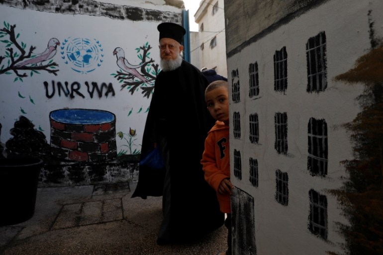 Palestinian man walks past a logo of United Nations Relief and Works Agency (UNRWA) in Jalazone refugee camp, near the West Bank city of Ramallah