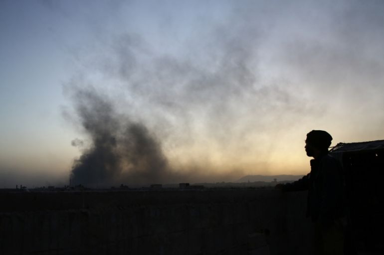 A man watches as smoke rises from Harasta area, as seen from Douma, in the eastern Damascus suburb of Ghouta