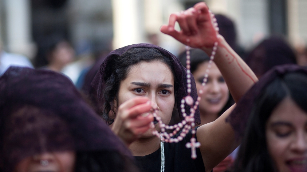 A demonstrator holds up a rosary in front of the Cathedral of Santiago during a protest against the pope's visit to Chile [File: Cristobal Saavedra Vogel/Reuters]