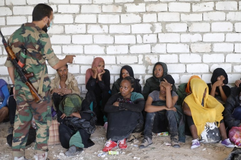 A Libyan soldier talks to African migrants after they were detained in Zawiya northern Libya