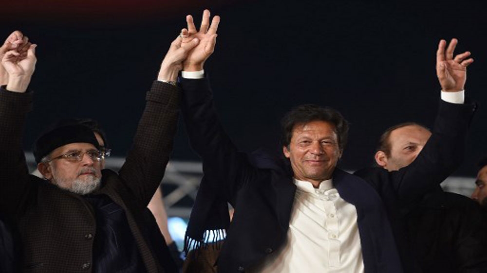 Cleric Tahir-ul Qadri (L) of Pakistan Awami Tehreek (PAT) and Pakistani opposition leader of Pakistan Tehreek-i-Insaf (PTI) Imran Khan raise hands during anti-government protest in Lahore [Arif Ali/AFP]