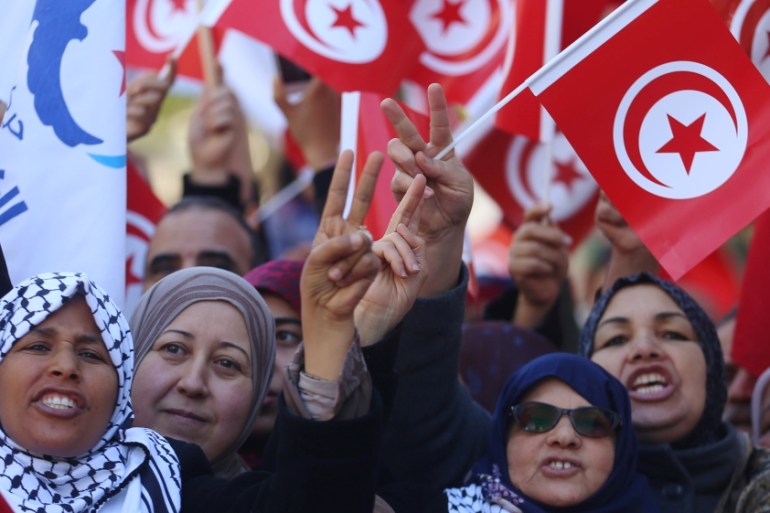 People wave national flags during demonstrations on the seventh anniversary of the toppling of president Zine El-Abidine Ben Ali, in Tunis