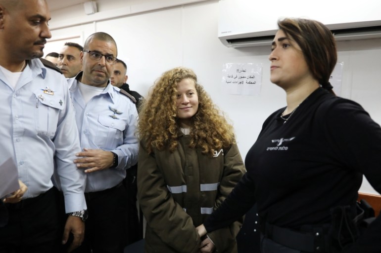 Palestinian teen Ahed Tamimi enters a military courtroom escorted by Israeli security personnel at Ofer Prison, near the West Bank city of Ramallah