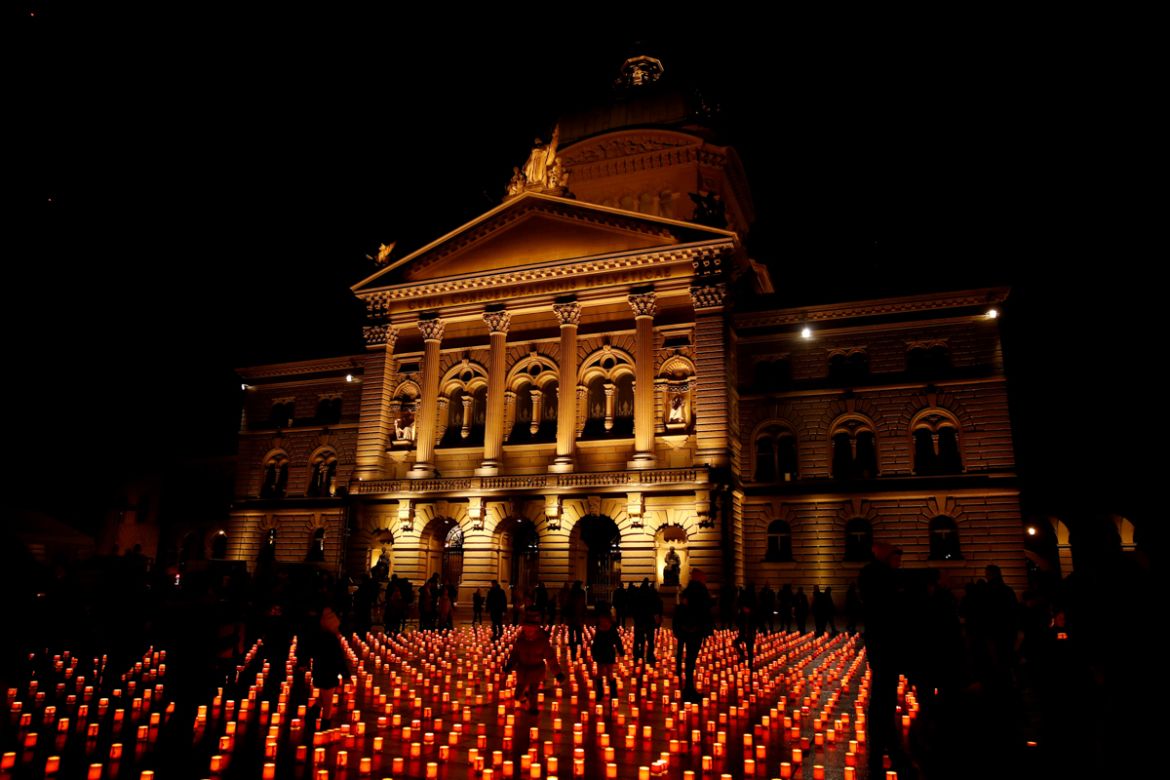 People walk between candles during the "One Million Stars" event by Swiss humanitarian organisation Caritas as a sign of solidarity and cohesion with the infirm and the poor, in front of the Swiss Fed