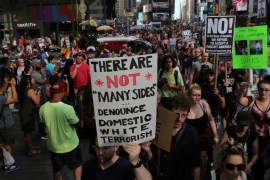 A protester holds a sign reading 'There are not 'many sides', Denounce domestic white terrorism' at a march against white nationalism in Times Square, August 13, 2017 [Joe Penney/Reuters] 