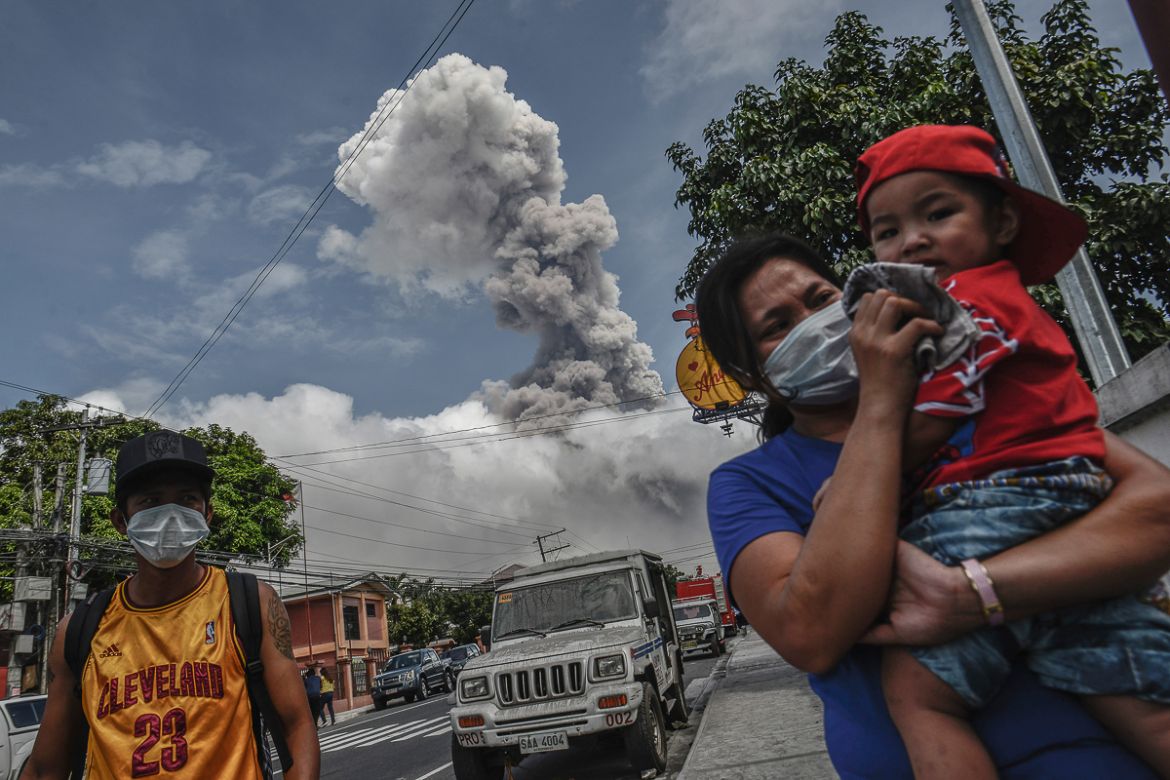 A woman covers the face of a child as Mount Mayon spews a huge column of ash noon in Camalig, Albay province, Philippines, January 24, 2018. Since Monday, January 22, the volcano has erupted in regula