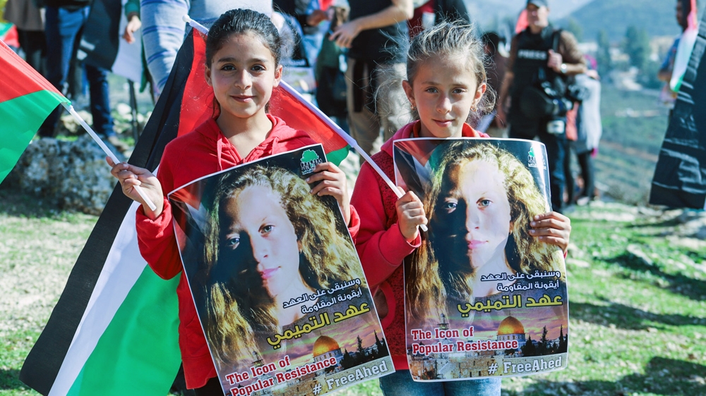 Two children hold up posters calling for Ahed Tamimi's release [Jaclynn Ashly/Al Jazeera] 