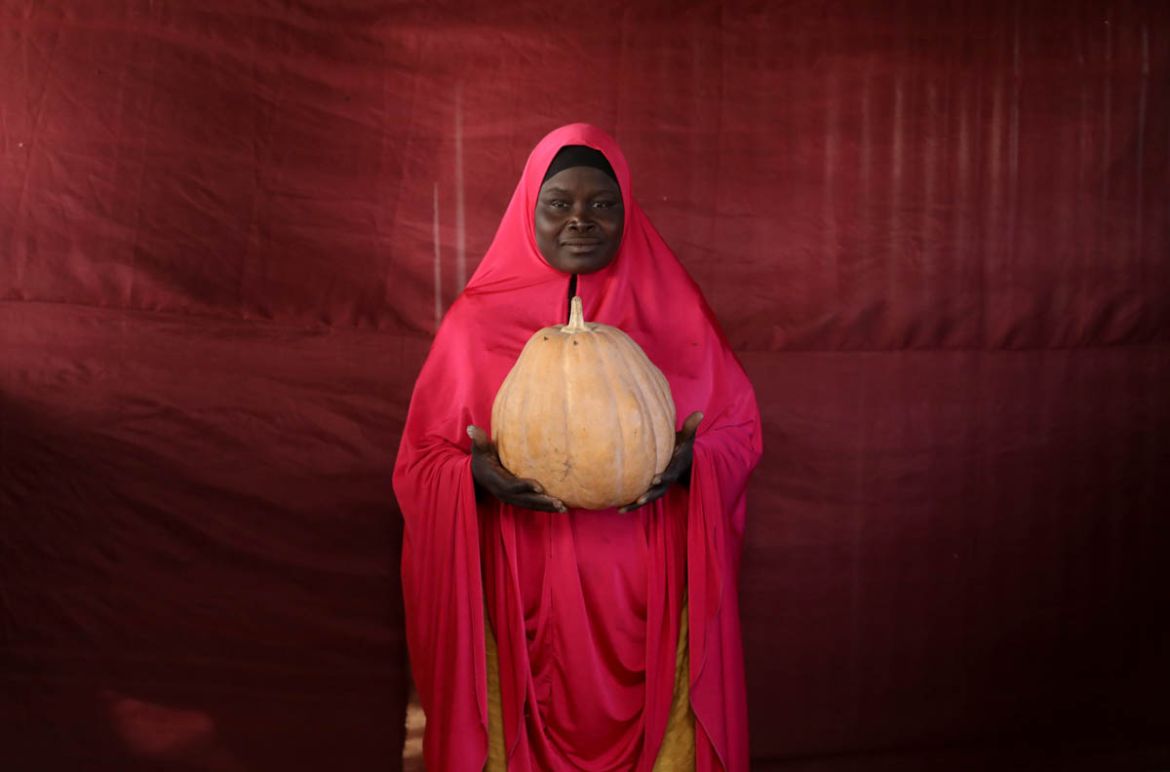 Aisha Umaru Gaye holds up a pumpkin. Cash cannot be king for the people of Bakasi camp. Instead, a small bundle of firewood can be traded for some milk. An unwanted bowl of baby fish is good in exchan