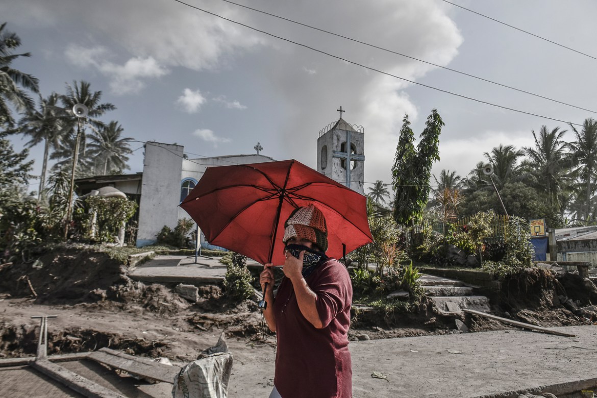 A woman uses an umbrella to shield herself from ashfall as Mount Mayon erupts in Guinobatan, Albay province, Philippines, January 23, 2018.