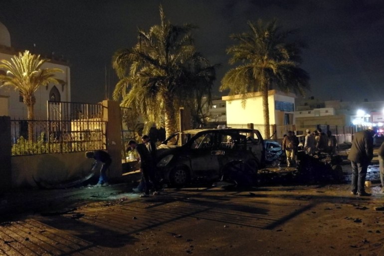 People inspect the site of twin car bombs in Benghazi