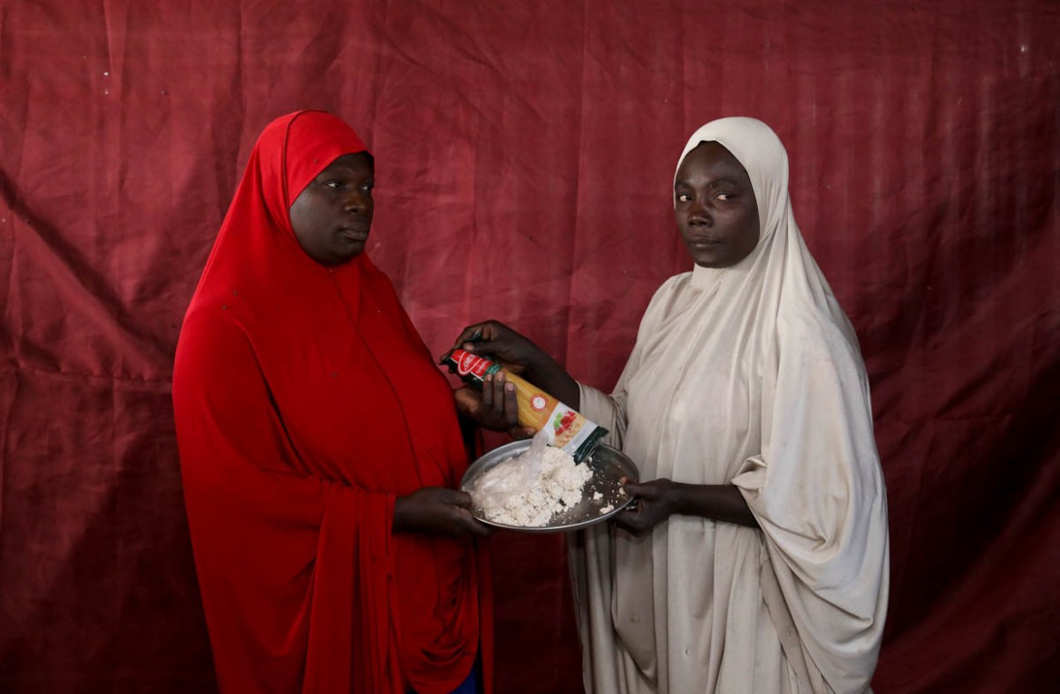 Zainab Umar gives parboiled soya bean paste to Aisha Jaule in exchange for spaghetti. REUTERS/Afolabi Sotunde