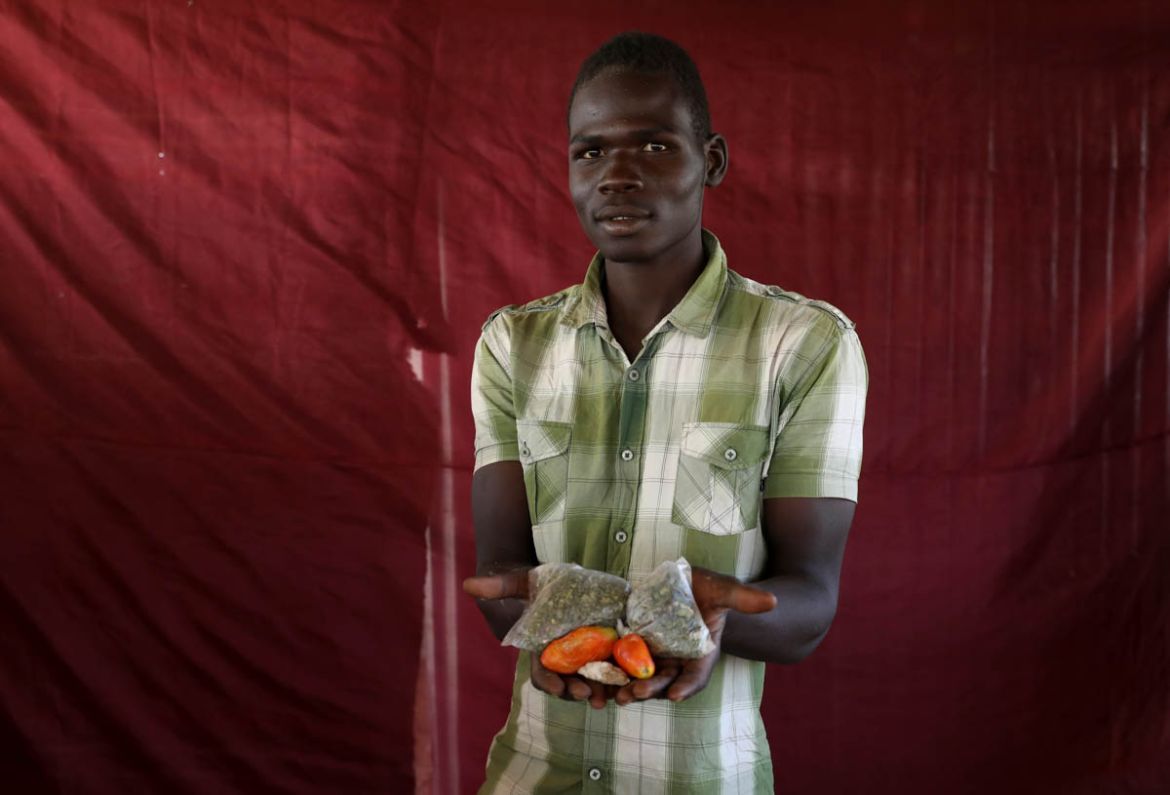 Mohammed Ali holds up two tomatoes and some dried vegetable leaves. REUTERS/Afolabi Sotunde