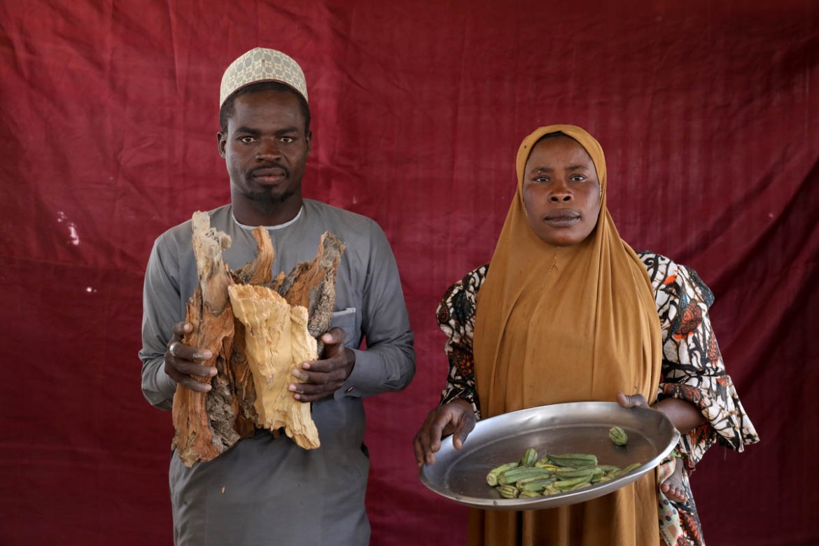Isa Zakariya Audu (L) holds pieces of firewood while Kakaye Ahmadu Maikifi holds up a plate of okra. REUTERS/Afolabi Sotunde