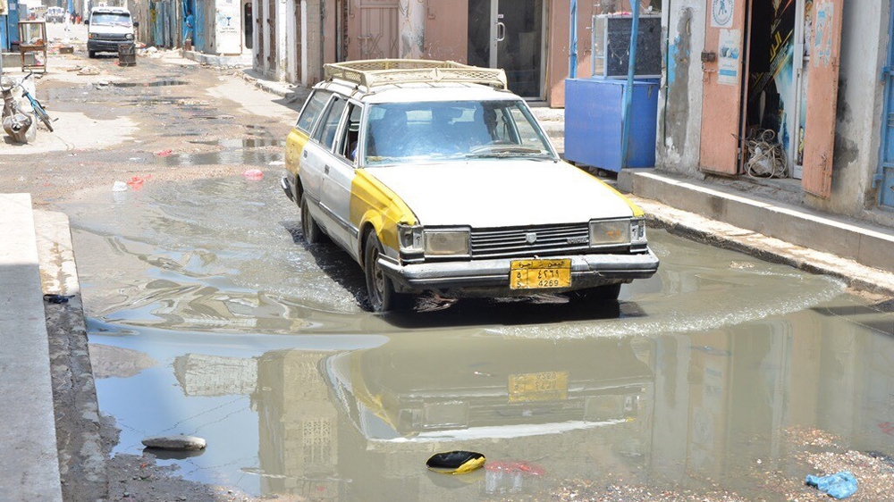 A taxi tries to drive along a narrow road in Mukalla full of rubbish and sewage [Rashed Bn Shbraq/Al Jazeera]