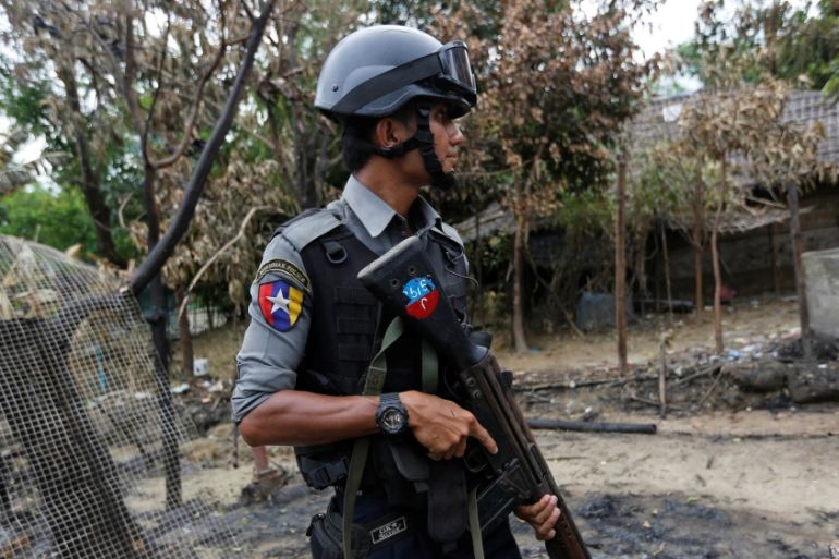 Police officer guards near a house which was burnt down during the last days of violence in Maungdaw