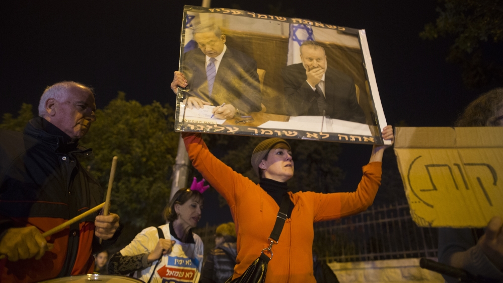 
An Israeli demonstrator holds a poster with a picture of Israeli PM Netanyahu (L) and Attorney-General Avichai Mandelblit during a protest against corruption in Jerusalem [Lior Mizrahi/Getty Images]
