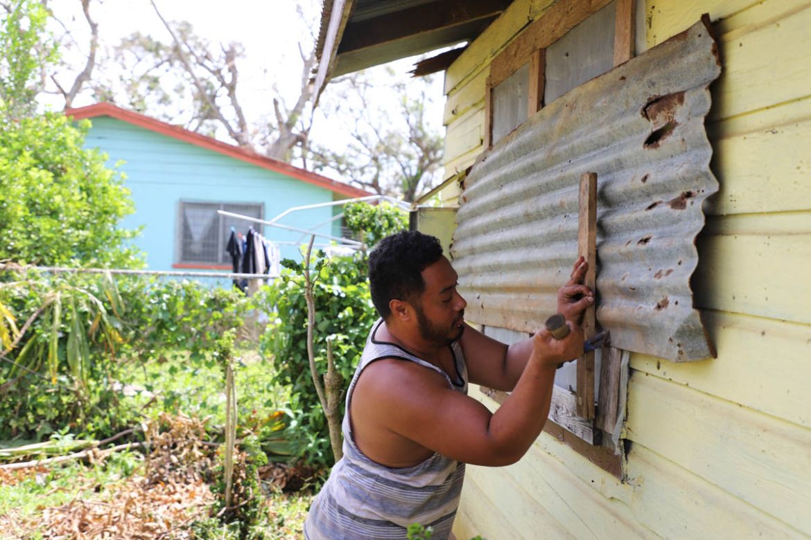 ''Ofa Filiai takes the corrugated iron protector off his windows. He and his family spent the night of Tropical Cyclone Gita in an evacuation centre and were relieved to return home and find the house