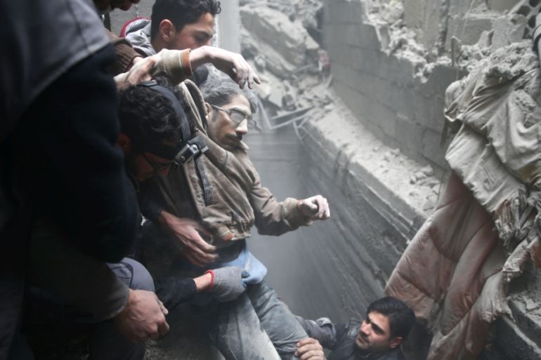 Civil defence help a man from a shelter in the besieged town of Douma