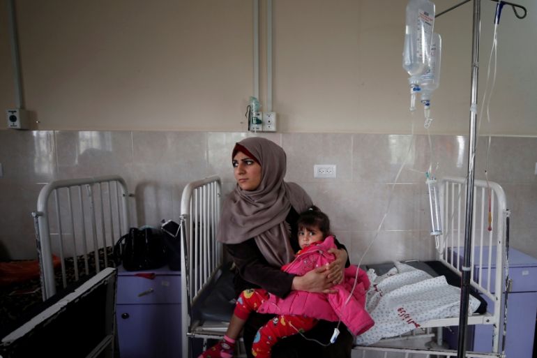A sick Palestinian girl is held by her mother inside a room at the Durra hospital in Gaza City