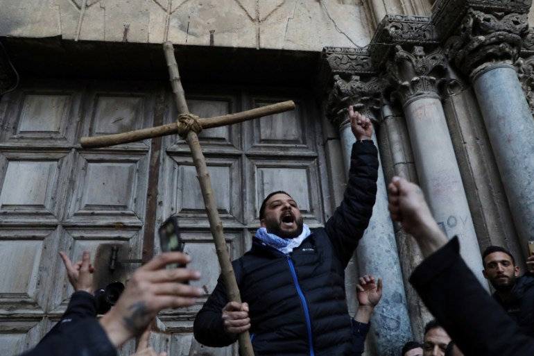 A worshipper holds a cross during a protest in front of the closed doors of the Church of the Holy Sepulchre in Jerusalem''s Old City