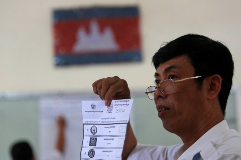 A member of the National Election Committee shows a ballot as he counts ballot papers during a Senate election in Phnom Penh