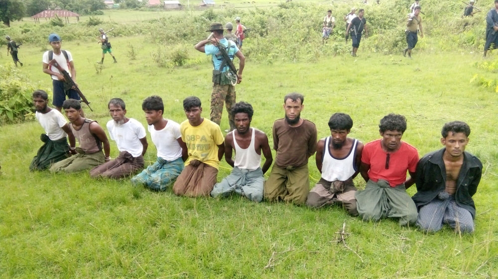 Ten Rohingya Muslim men with their hands bound kneel as members of the Myanmar security forces stand guard in Inn Din village [Reuters]