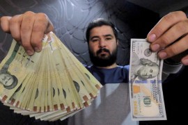 Money changer poses for the camera with U.S hundred dollar bill and the amount being given when converting it into Iranian rials, at a currency exchange shop in Tehran''s business district, Iran