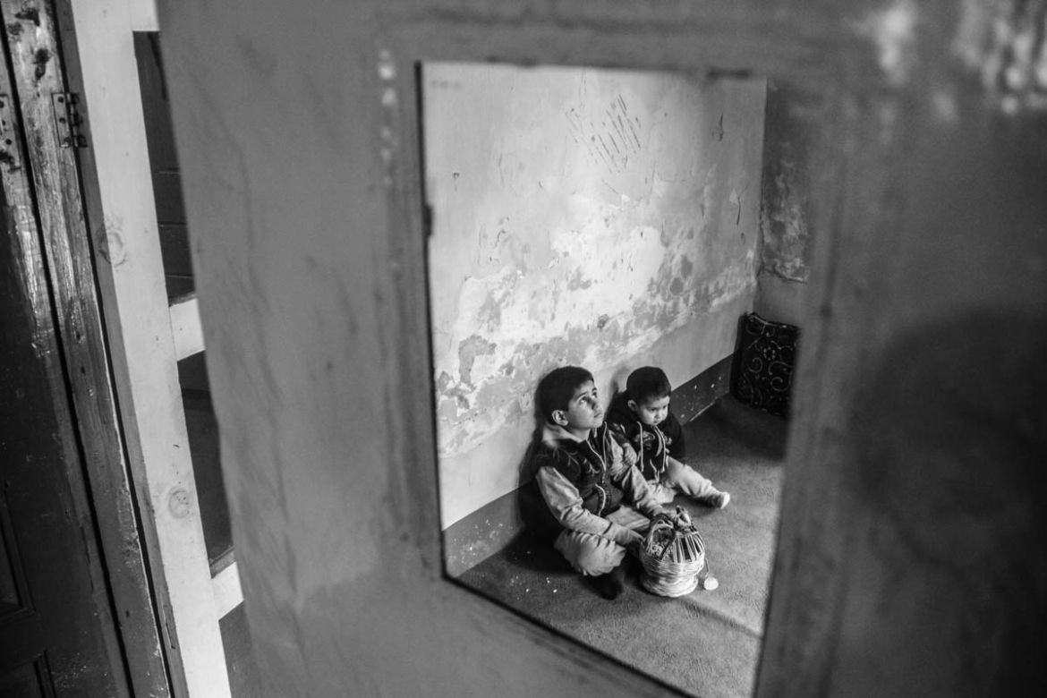 Suhaib and Iffaq sitting inside living room of their house warming hands on a fire pot. Their father was killed on July 9 in village Akad of Anantnag, about 62 km south of Srinagar city, the summer ca
