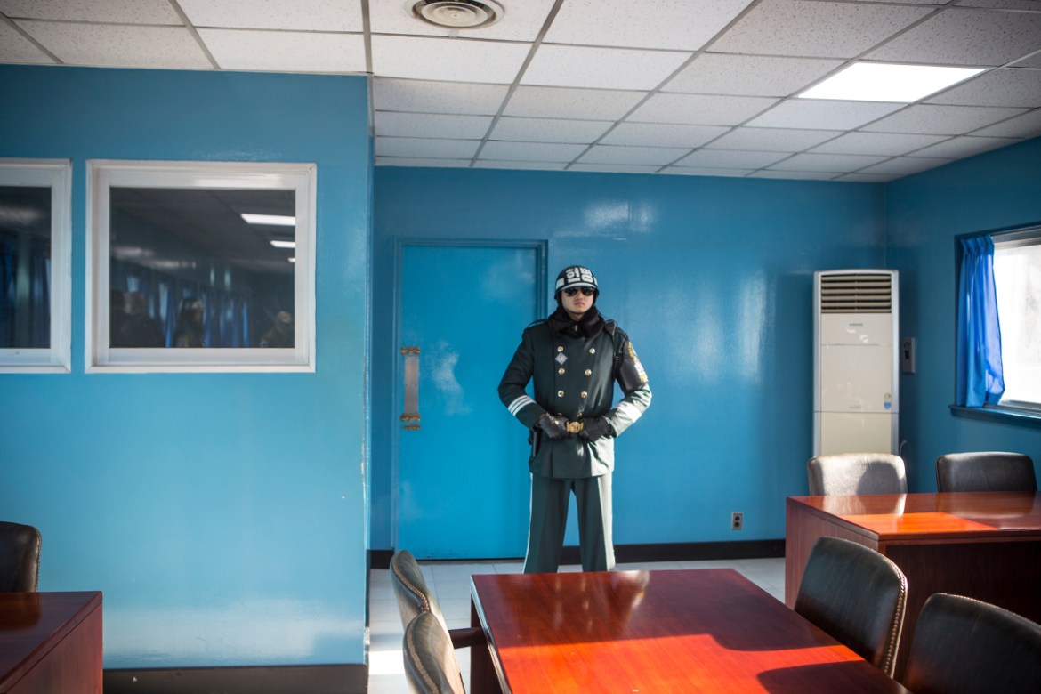 Inside the conference room – half of which is on North Korea’s side of the MDL – a soldier stands guard by the door that leads to North Korea. The taekwondo pose and dark shades form a military proced