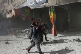 A man runs as he holds a girl after an airstrike in the besieged town of Douma in eastern Ghouta in Damascus