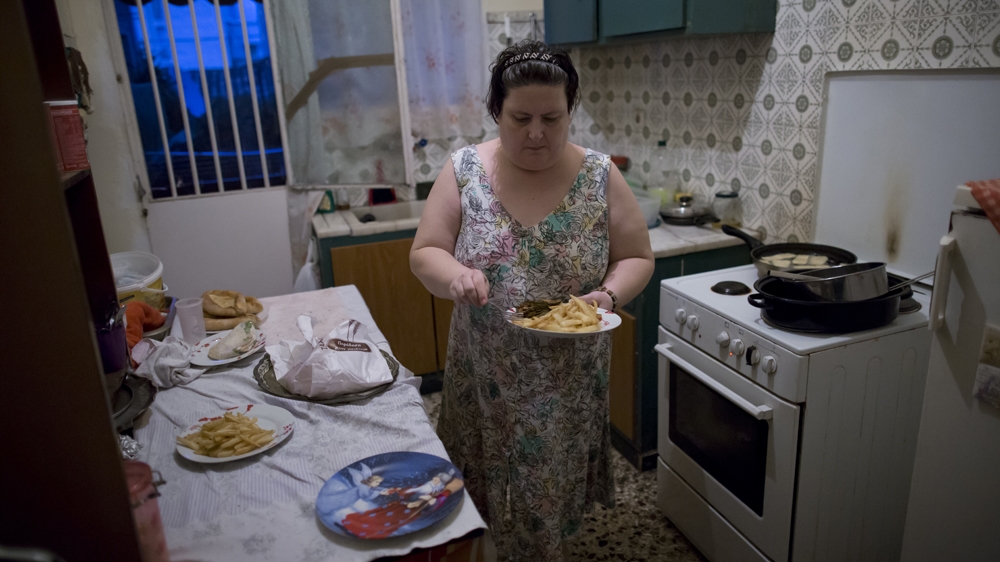 Ioanna prepares a meal she put together from handouts [Yannis Kolesidis/Al Jazeera] 