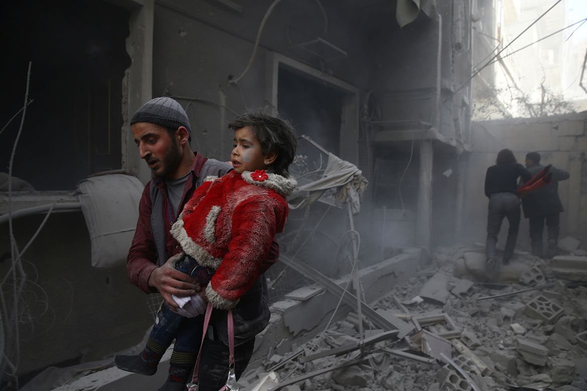 A man holds a child after an airstrike in the besieged town of Douma in eastern Ghouta in Damascus, Syria, February 7, 2018. REUTERS/ Bassam Khabieh