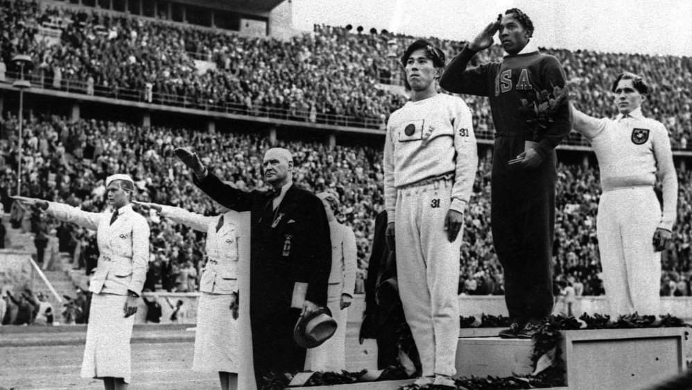 Gold medalist Owens on the podium during the medals ceremony at the 1936 Summer Olympics in Berlin [AP Photo]