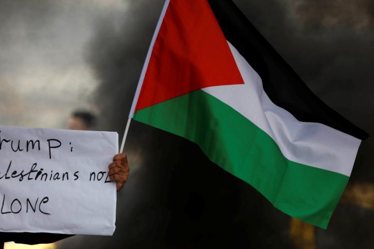 A demonstrator holds a sign and a Palestinian flag at a protest against Trump''s decision to recognise Jerusalem as the capital of Israel, near the West Bank city of Nablus [File: Mohamad Torokman/Reu