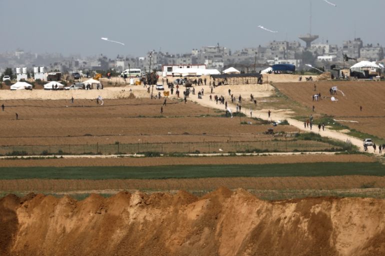 Palestinians walk near a tent camp on the Gaza side of the Israel-Gaza Strip border, as seen from the Israeli side of the border