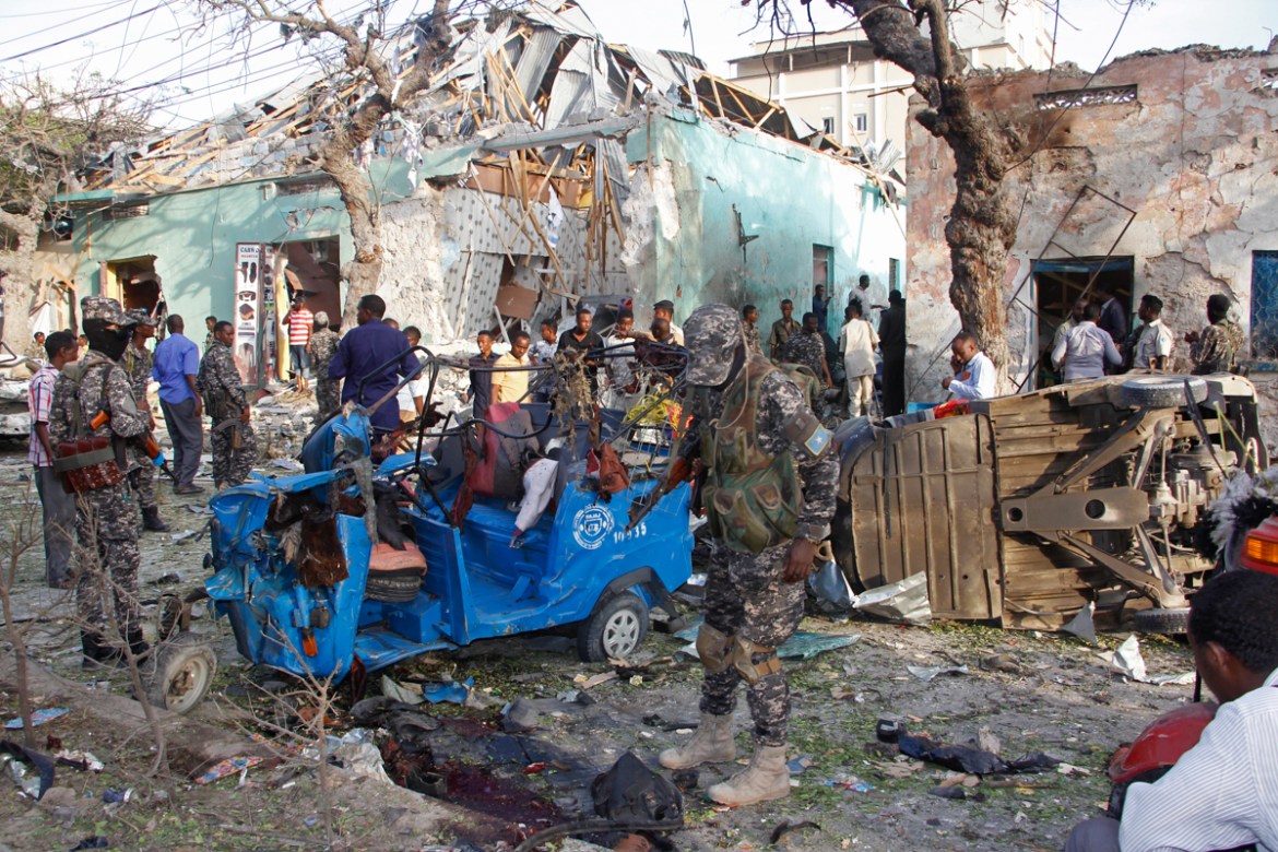 Somalis stand outside a destroyed building after a car bomb in Mogadishu, Somalia Thursday, March 22, 2018. Somali officials say at least 14 people have been killed and 10 others are wounded in a car