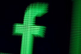 FILE PHOTO: A 3D-printed Facebook logo are seen in front of displayed binary digits in this illustration