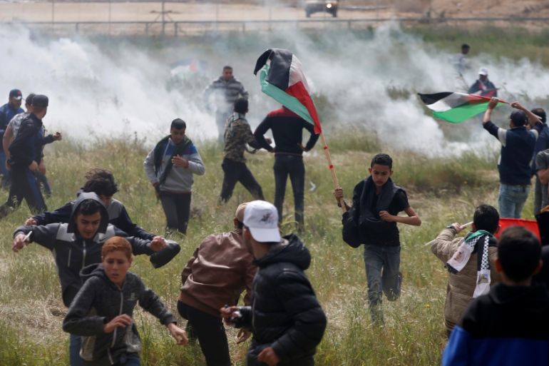 Palestinians run from tear gas fired by Israeli troops during clashes, during a tent city protest along the Israel border with Gaza, demanding the right to return to their homeland, east of Gaza City