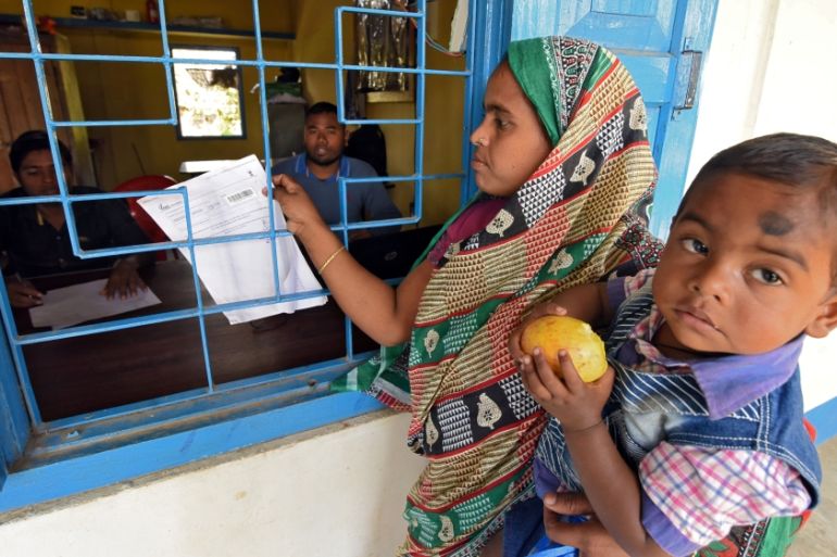 A woman carrying her son arrives to check her name on the draft list of the National Register of Citizens at an NRC centre in Chandamari village