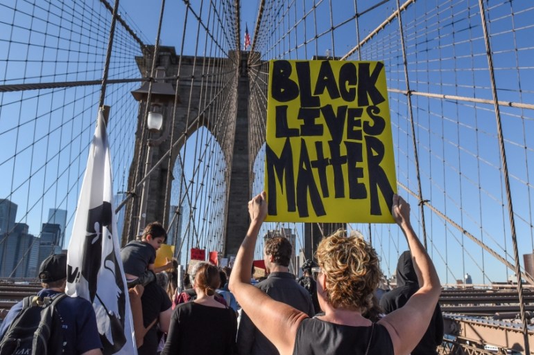 A person carrying a Black Lives Matter sign participates in a protest called March for Racial Justice while walking over the Brooklyn Bridge in New York City