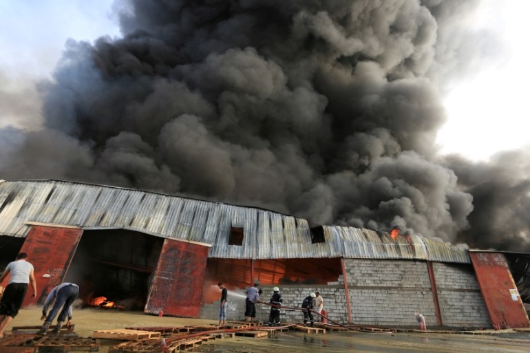 Firefighters try to extinguish a fire engulfing warehouse of the World Food Programme in Hodeida, Yemen