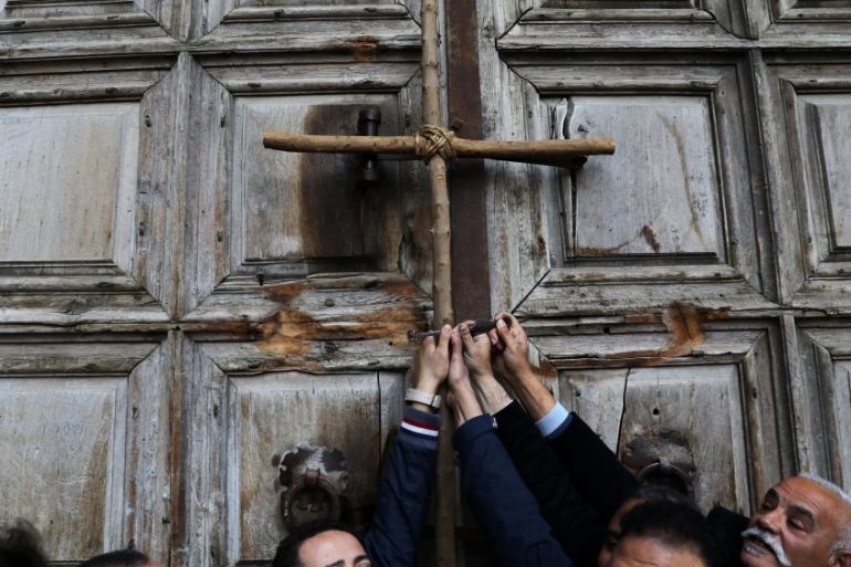 Worshippers hold a cross during a protest in front of the closed doors of the Church of the Holy Sepulchre in Jerusalem''s Old City