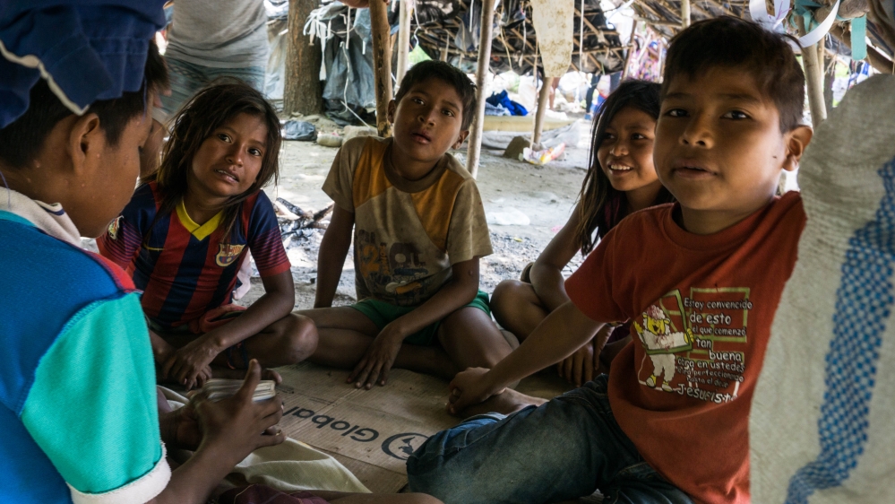 A group of Yukpa children play cards to pass time in one of the makeshift tents [Bram Ebus/Al Jazeera]