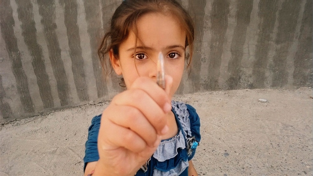 War, militias and other armed groups made life in Jalawla city difficult for civilians. One of Nori's daughters holds a bullet she found in the street [Screengrab/Al Jazeera]