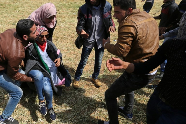 A wounded Palestinian woman is evacuated during clashes with Israeli troops, during a tent city protest along the Israel border with Gaza