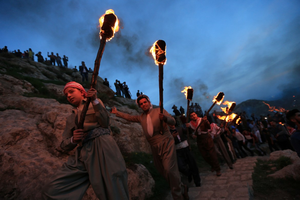 Iraqi Kurdish people carry fire torches up a mountain, as they celebrate Newroz Day, a festival marking the begining of spring and the vernal equinox, in the town of Akra, Iraq. [Ari Jalal/ Reuters]