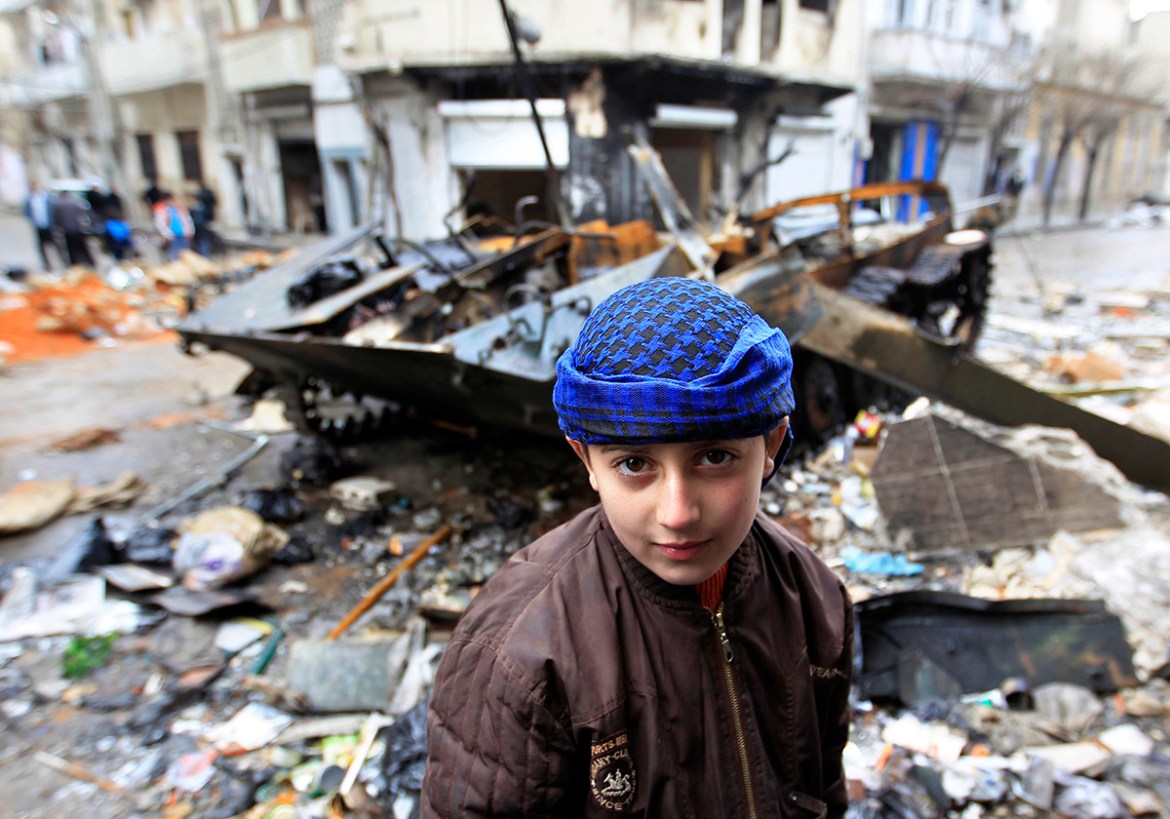 A Syrian boy stands in front of a damaged armoured vehicle belonging to the Syrian army in a street in Homs January 23, 2012. Syria on Monday rebuffed as a "conspiracy" an Arab League call for Preside