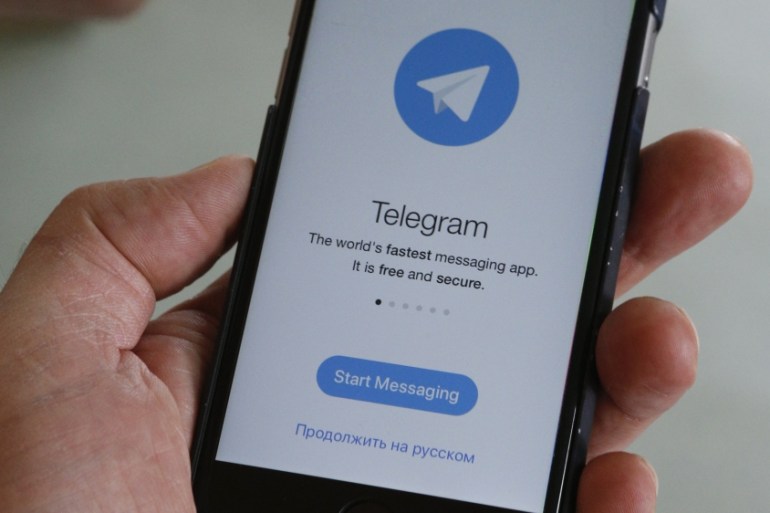 People pose with smartphones, with the Telegram logo seen on a screen, in this picture illustration