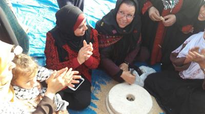 Iktimal Hamad, head of the Women's Committee grinds some wheat in one of the tents in Gaza near the Israeli border. [Courtesy of Women's Committee of Great Return March]
