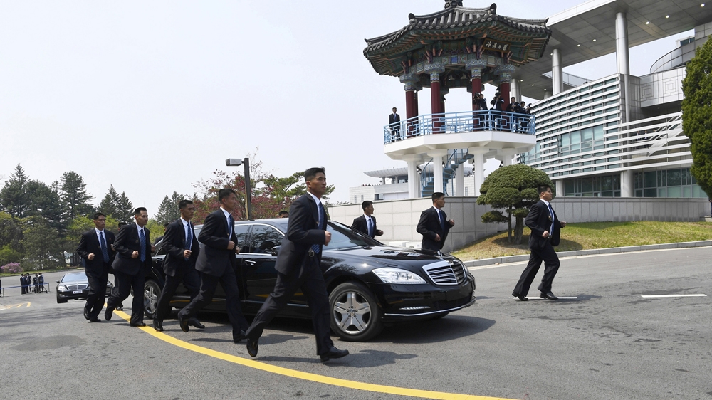 Bodyguards jog alongside Kim Jong-un's limousine as he returns north for lunch [Korea Summit Press Pool via The Associated Press]